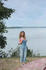 curly woman in denim overalls outdoors