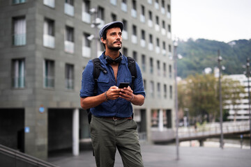 Young stylish man using the phone outdoors. Fashion happy businessman outdoors