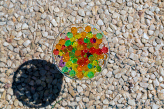 glass cup placed on a pebble floor, filled with colored beads (orbis) with selective focusing
