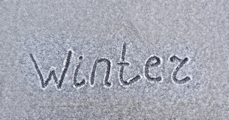 Handwriten word, Wintter text on snowy surface. Winter coming
