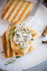 fried bread toast with cheese spread with boiled dried mushrooms on a wooden table.