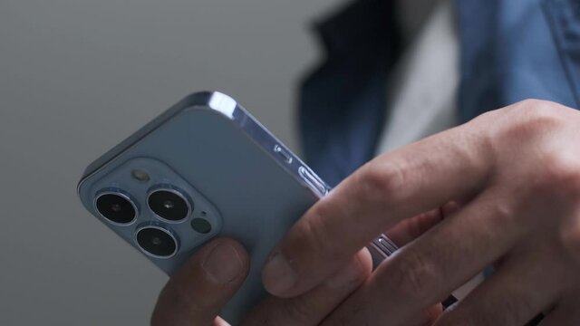 New Iphone 13 Pro smart phone in Sierra Blue color filmed in 4K. Young man using trendy Apple mobile phone with three lenses in close up video clip