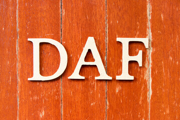Alphabet letter in word DAF (Abbreviation of Delivered at frontier) on old red color wood plate...