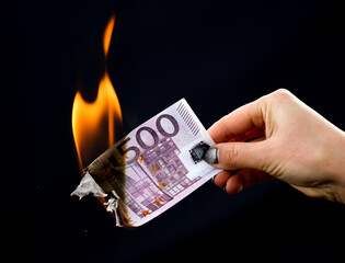 Five hundred Euros are burning with fire in hand isolated on black