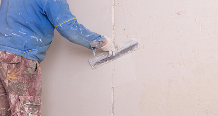 The man is plastering the walls