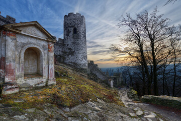 Station of the Cross and lower tower of Bezděz gothic castle with dramatic background of sunset sky