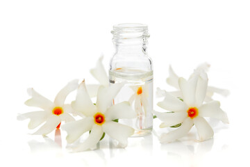 Micro close-up of Essential Oil or Attar, Fragrance Oil, Perfume oil in mini transparent glass bottle of orange small night blooming flower Parijat or Harshringar (Nyctanthes arbor-tristis)