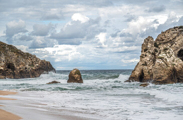 Ocean water splash on rock beach with beautiful sky and clouds. Sea wave splashing on stone at sea shore on winter. rocky coastline with white water swirling around the rocks