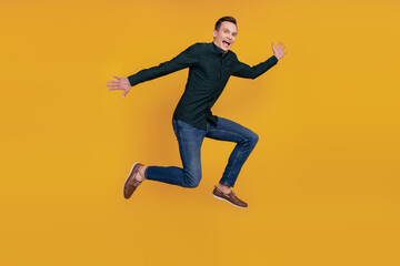 Full size profile side photo of young cheerful man have fun excited fly air jump up active isolated over yellow color background