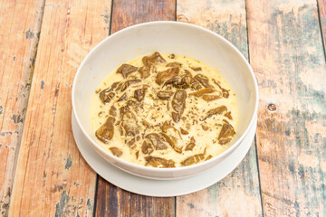 Boletus edulis stew with cream cheese in white bowl on wooden table