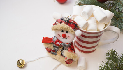 Traditional hot chocolate with marshmallows and a snowman on a white textured background. Christmas drink theme.