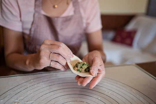 Faceless female cook stuffing dough with meat