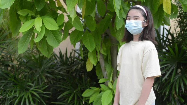 A girl wearing a mask showing greetings to friends by hitting each other with their elbows. Instead of the usual handshake to prevent the spread of the coronavirus.