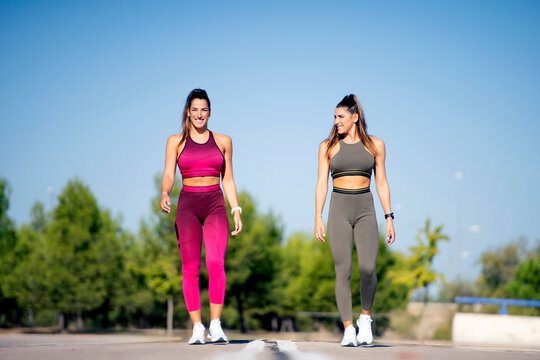 Cheerful sporty twins standing on asphalt