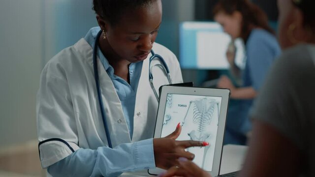 Woman working as doctor holding tablet with skeleton image for osteopathy diagnosis. Medic explaining human bones structure and anatomy for orthopedic examination on modern gadget.