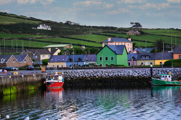 Various colorful houses and boats lining DIngle Bay in Dingle, Ireland.
