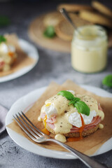Egg benedict sandwiches - muffin with poached egg, ham and hollandaise sauce