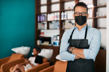Portrait of confident male hairdresser with protective face mask at hair salon.