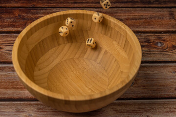 Wooden bowl with white striped dish towel on wooden table and dice