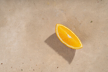 Fototapeta na wymiar A slice of orange on a sandy beige background. View from above
