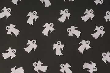 Pattern made of smiling ghost figures on a black backgorund. Halloween concept.