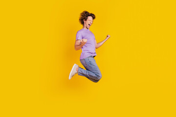 Photo of cheerful astonished man jump celebrate victory wear casual jeans clothes on yellow background