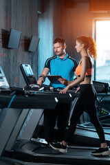 Fototapeta na wymiar young beautiful woman has workout on treadmill with personal trainer and running