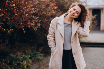 Pretty woman with curly hair walking in an autumn coat