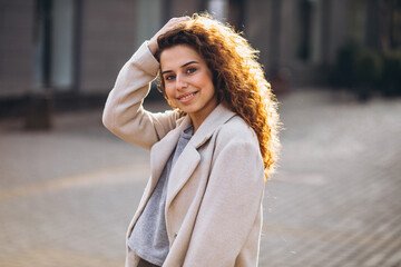 Fototapeta premium Pretty woman with curly hair walking in an autumn coat