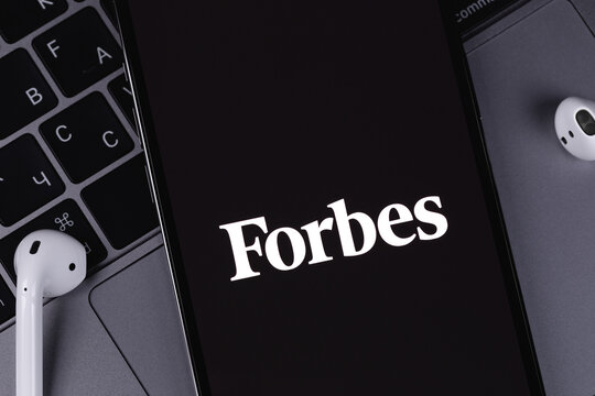 Forbes logo mobile app on screen smartphone iPhone with notebook keyboard closeup. Forbes is an American family-controlled business magazine. Moscow, Russia - July 22, 2021