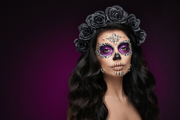 Portrait of a woman with sugar skull makeup over purple background. Halloween costume and make-up. Portrait of Calavera Catrina
