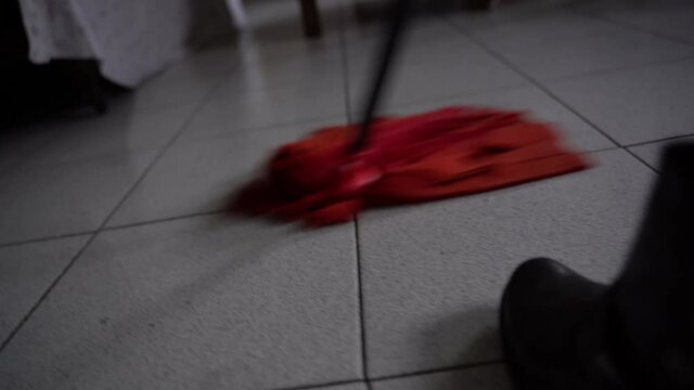 Janitor in black boots asking floor in apartment or office room, busy housekeeper using wet red mop for cleaning dirty floor. Maid cleansing floor with disinfectant detergent and mop, general cleanup