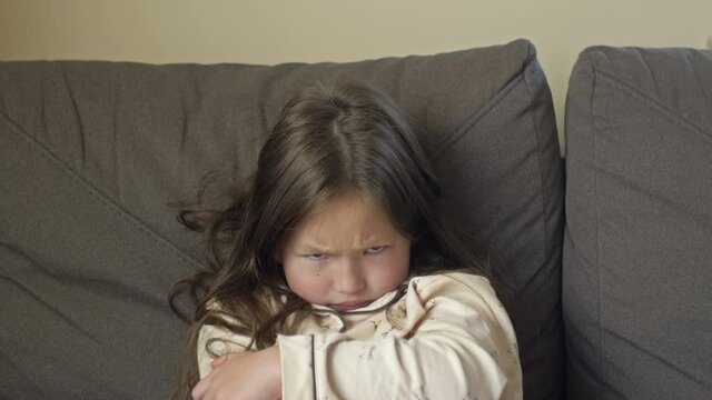 Portrait of an angry girl 6-7 years old after sleep in pajamas.