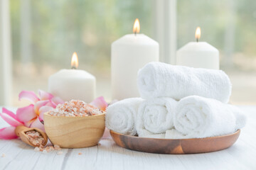 Fototapeta na wymiar Natural relaxing spa composition on massage table in wellness center with towels, flowers and salt, candle on massage table in spa salon.