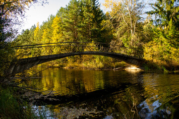 Old vintage bridge over the river. Autumn forest architectural landscape