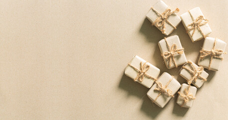 brown gift,Brown christmas gift,Gift boxes wrapped in kraft paper with white, silver and golden ribbon and bow on pastel beige background. Blank gift tag for text. Holiday present concept. Top view.