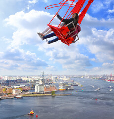 People on red seesaw swinging high in the air space against beautiful blue sky above the town. Amsterdam. Netherlands. Inspiration, love and dreams - obrazy, fototapety, plakaty