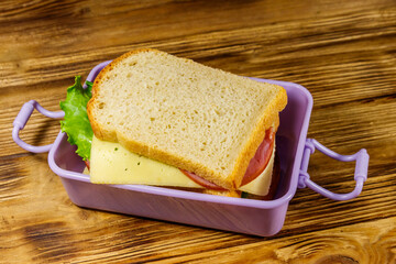Lunch box with sandwiches on a wooden table