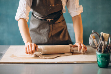 Young woman on a pottery class working with rolling pin