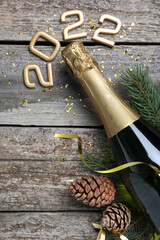 Happy New Year 2022! Flat lay composition with bottle of sparkling wine on wooden table