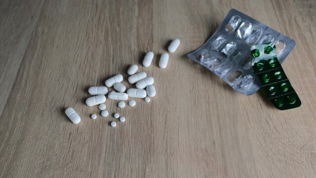 closeup female hands holding, pouring out many white tablets, pills, drugs, capsules, concept of maintaining health, medication treatment, vitamins, deliberate drug overdose