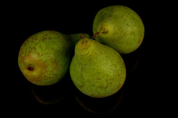 Three juicy green pears on a black background