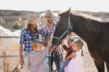 Family enjoy day at horse ranch - Farmer parents with children outdoor - Animal love and care