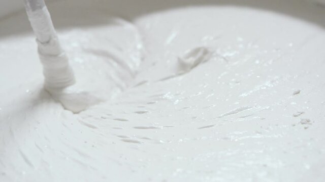 White finishing putty is mixed in a bucket