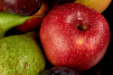Fresh fruits. Green pears, red and yellow apples, blue plums. Water drops on fruits. Close-up