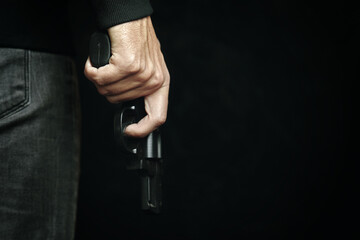 Criminal with revolver in his hand. Firearm for defense or attack. Killer on black background. Man...