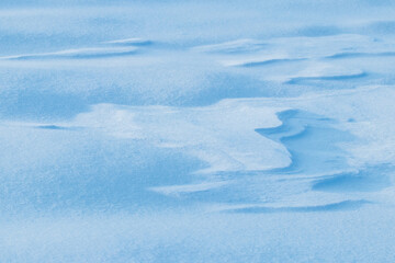 Snowy background, snow-covered surface of the earth after a blizzard in the morning in the sunlight with distinct layers of snow