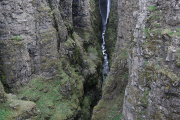 wąski wodospad glymur w islandii spływający po omszonych skałach