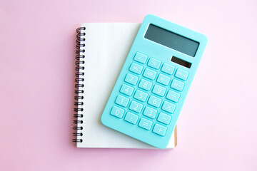 Mint calculator and notebook isolated on pink background. Concept of family budget and payment of taxes, investments. Top view