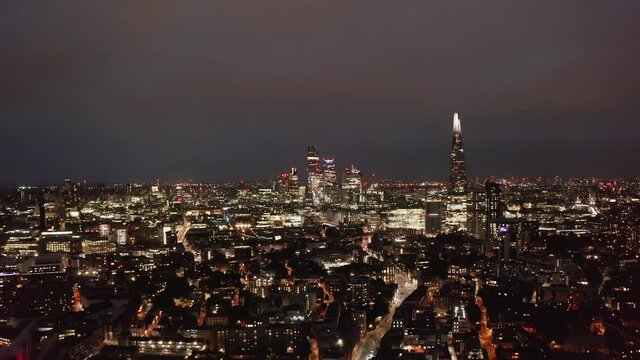 Amazing aerial panoramic shot of night city. Illuminated tall downtown skyscrapers and traffic in streets. London, UK